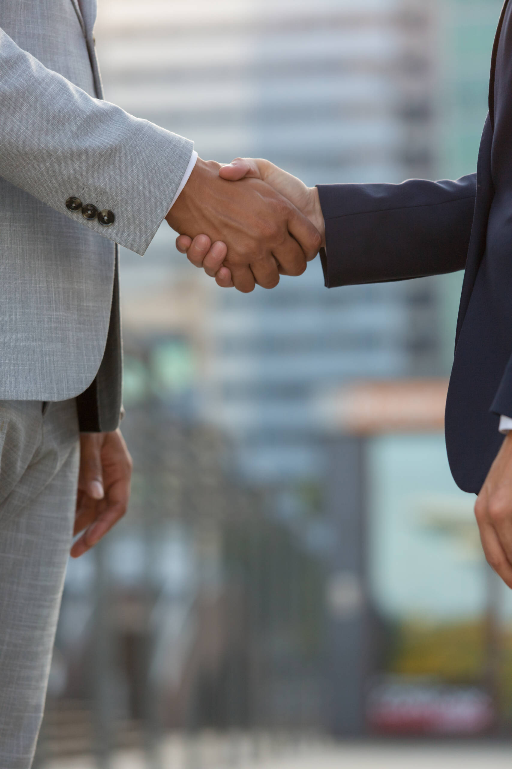 Businesspeople standing in city street and shaking hands. Business man and woman in office suits meeting outside. Successful partnership concept